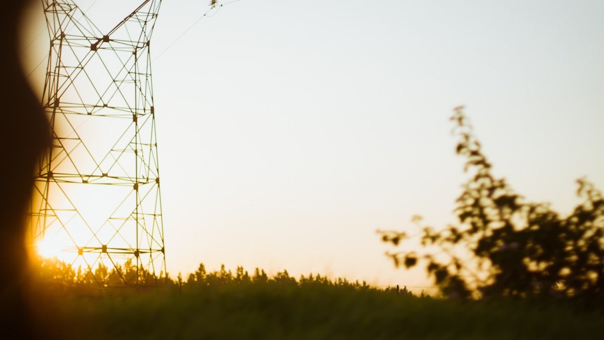 Power tower silhouetted against a soft sunset sky.